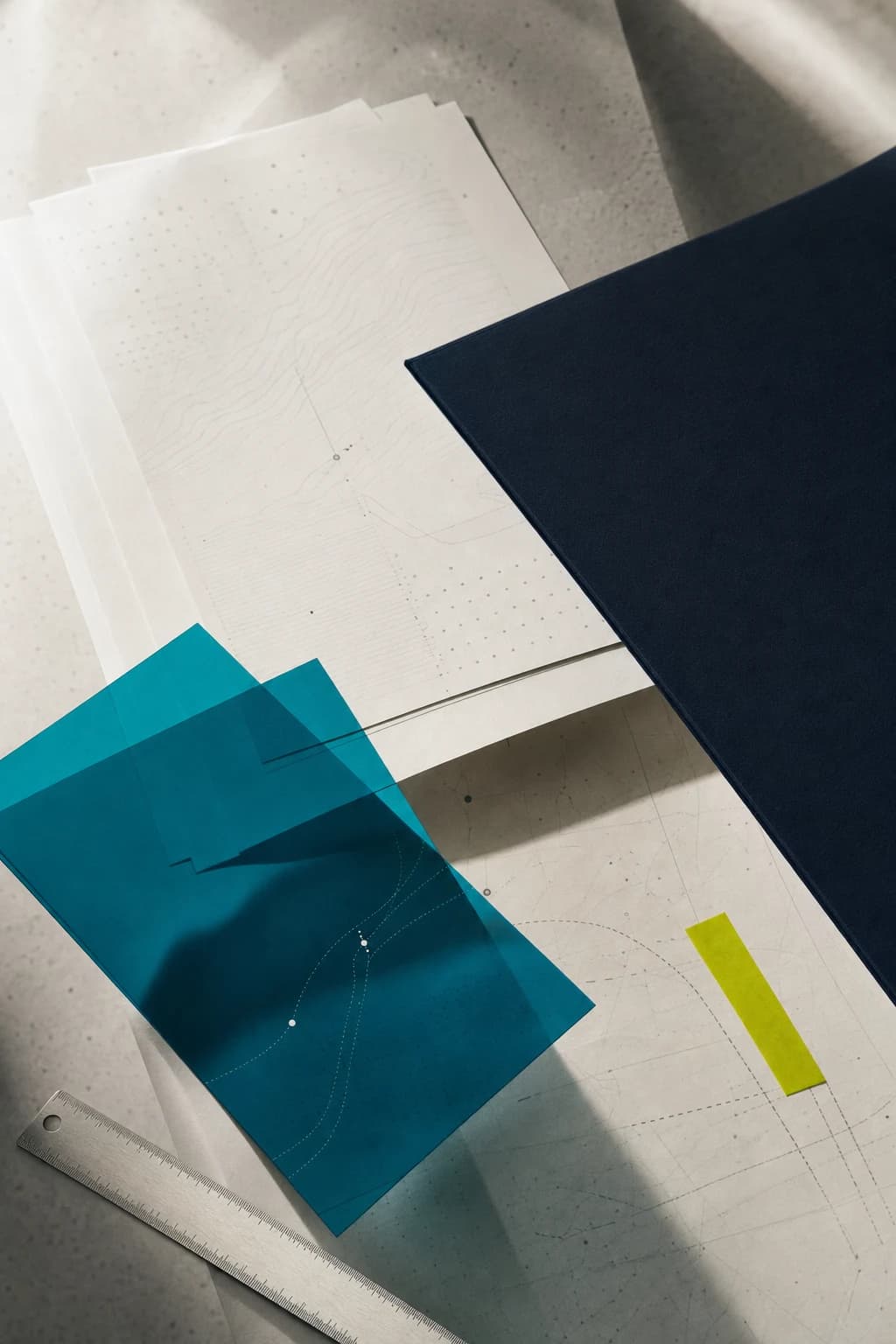 Layered regulatory papers, a navy folder, and teal working sheets on an advisory desk